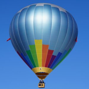 A vibrant hot air balloon gracefully floats against a clear blue sky, evoking a sense of freedom.
